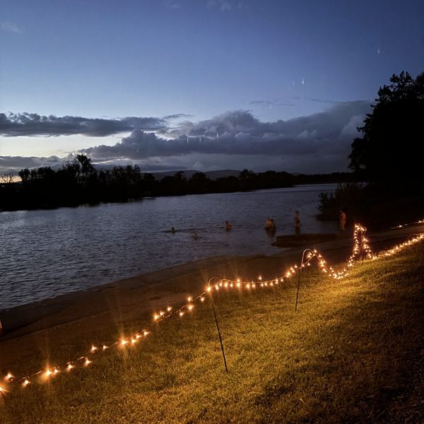 Fairy lights along the riverbank at dusk