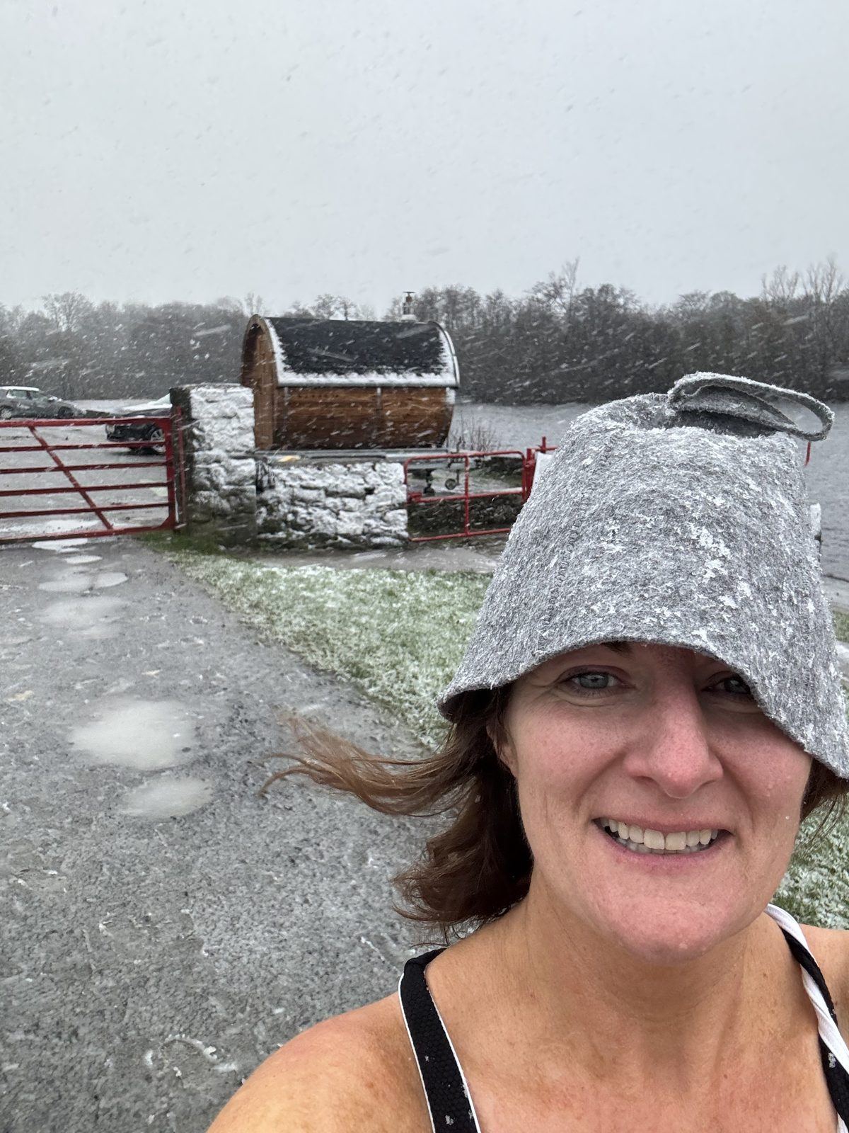 Aine in her sauna hat in the snow beside the sauna